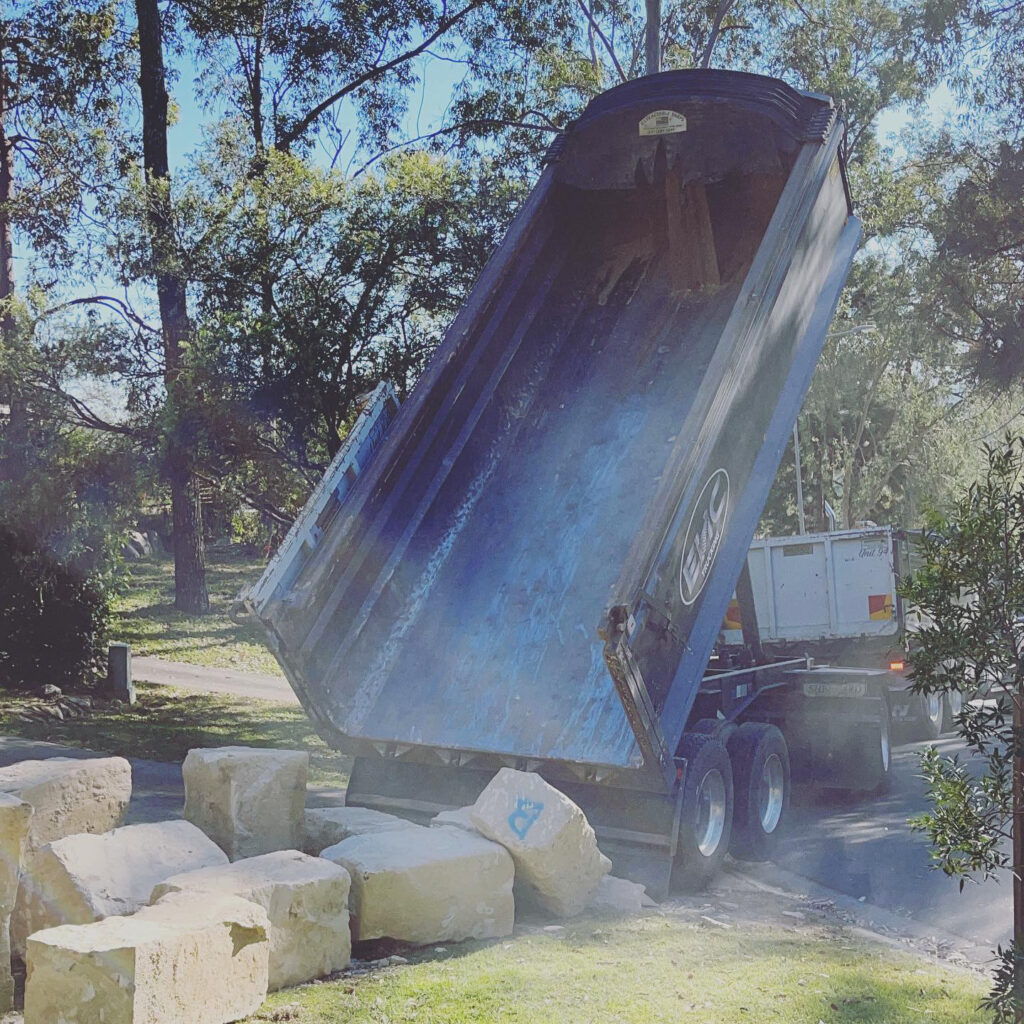 tipping off sandstone blocks using a tipper truck on grass